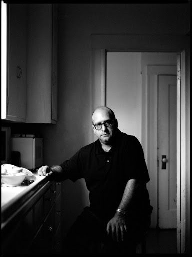 Fotografía nocturna de una casa suburbana con una ventana iluminada entre la niebla, estilo "House Hunting" de Todd Hido